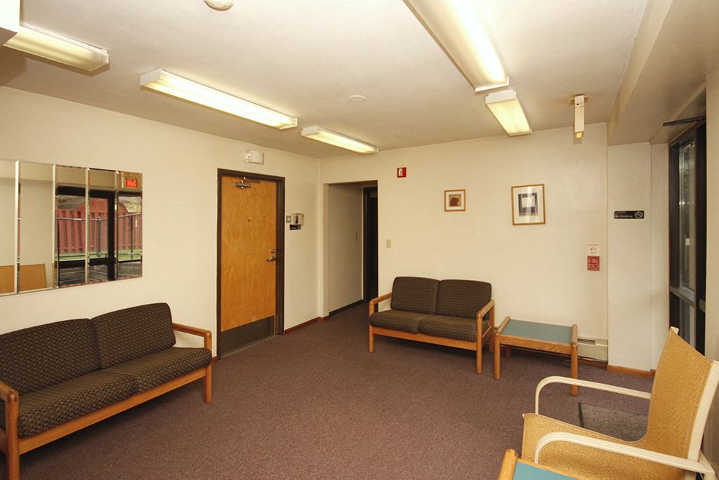 a waiting room with couches and chairs and a door
